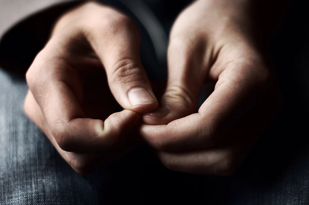A close-up of hands resting anxiously in a lap, reflecting the emotional challenges faced during addiction and the personal recovery journeys shared in client stories. 