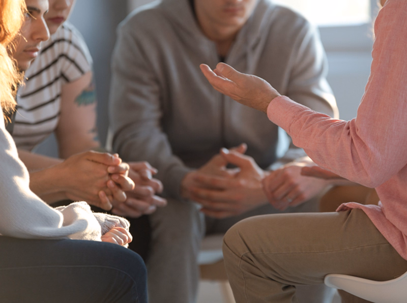 Group therapy session discussing addiction recovery.