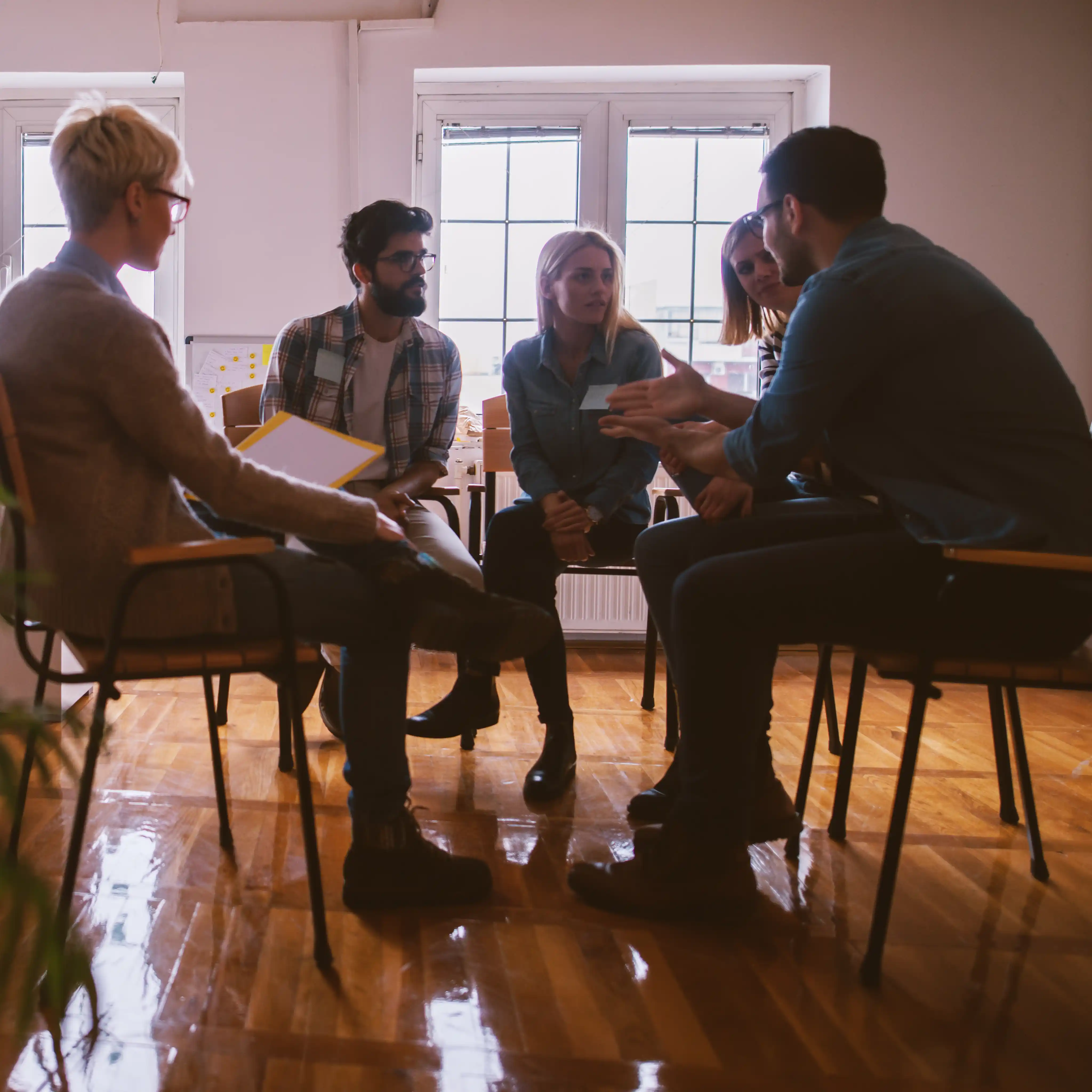 A group of young adults sit together in a therapy session, supporting each other in their recovery from marijuana addiction, highlighting the role of family and community in the healing journey.