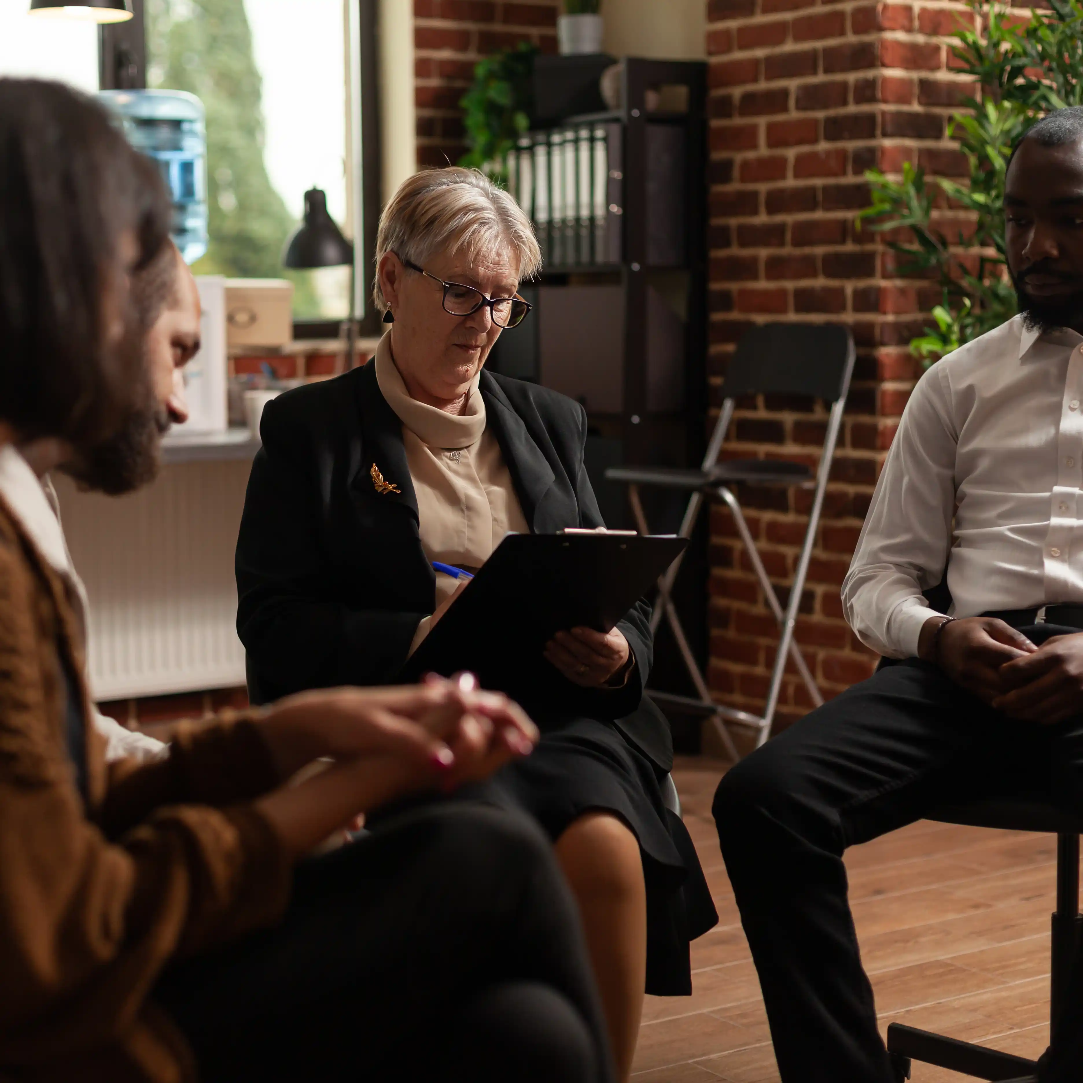 A female therapist speaks with care and focus during a group therapy session, offering guidance to participants seated in a supportive circle. The image reflects the importance of therapeutic connection and shared recovery in addressing dopamine-related behavioural addictions.