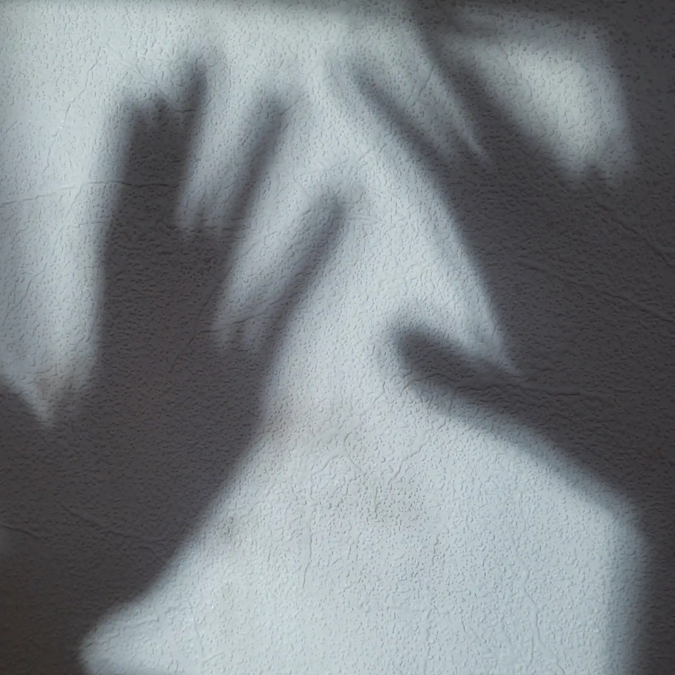 A person’s POV as they’re looking at the glimmering shadows of their hands on a wall.