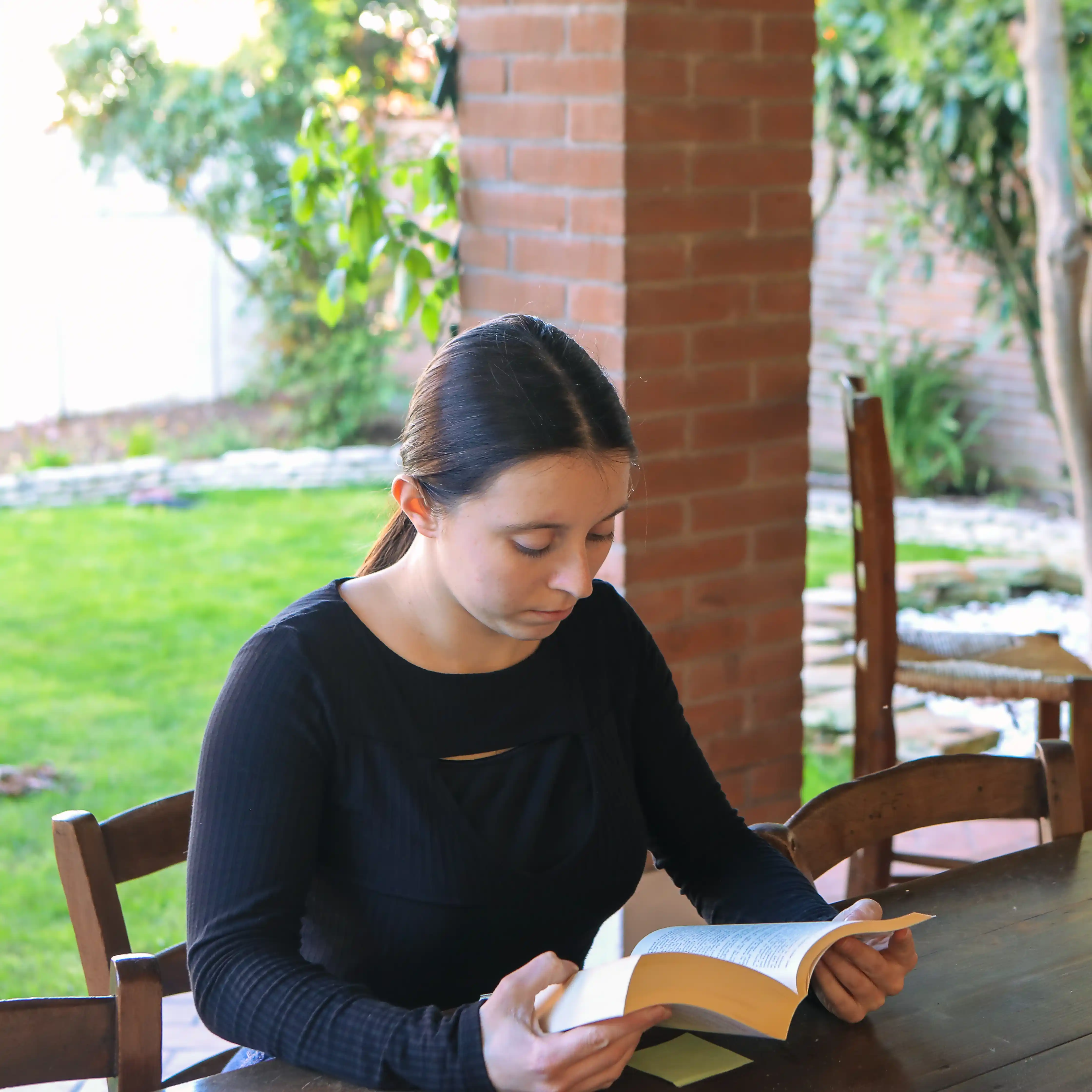 An MDMA rehab client in a garden setting in the afternoon. They’re engrossed in a book, doing their best to keep their focus and to practice their mindfulness.