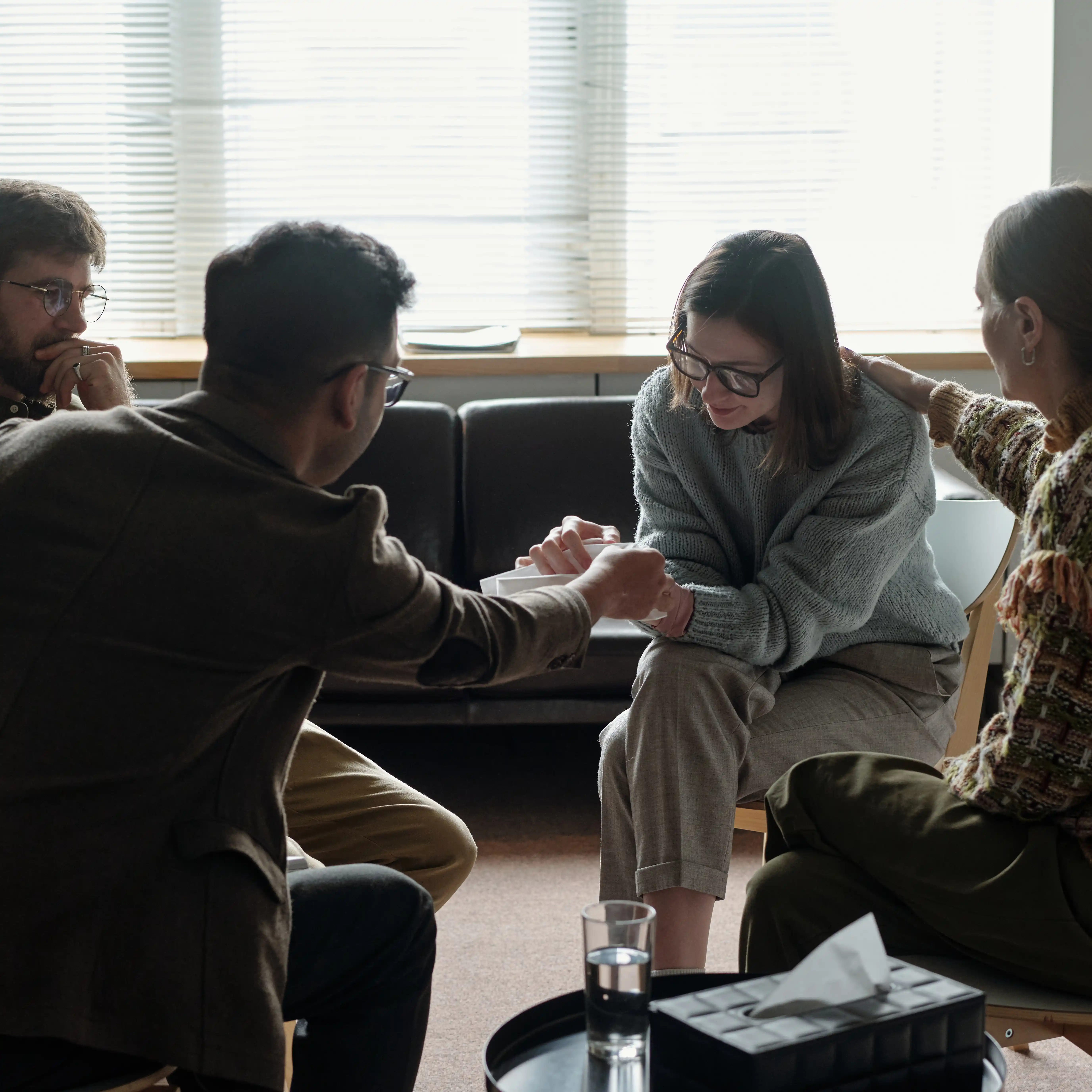 A person in their 20s in group therapy. They’re sharing a difficult memory and people are listening supportively. 