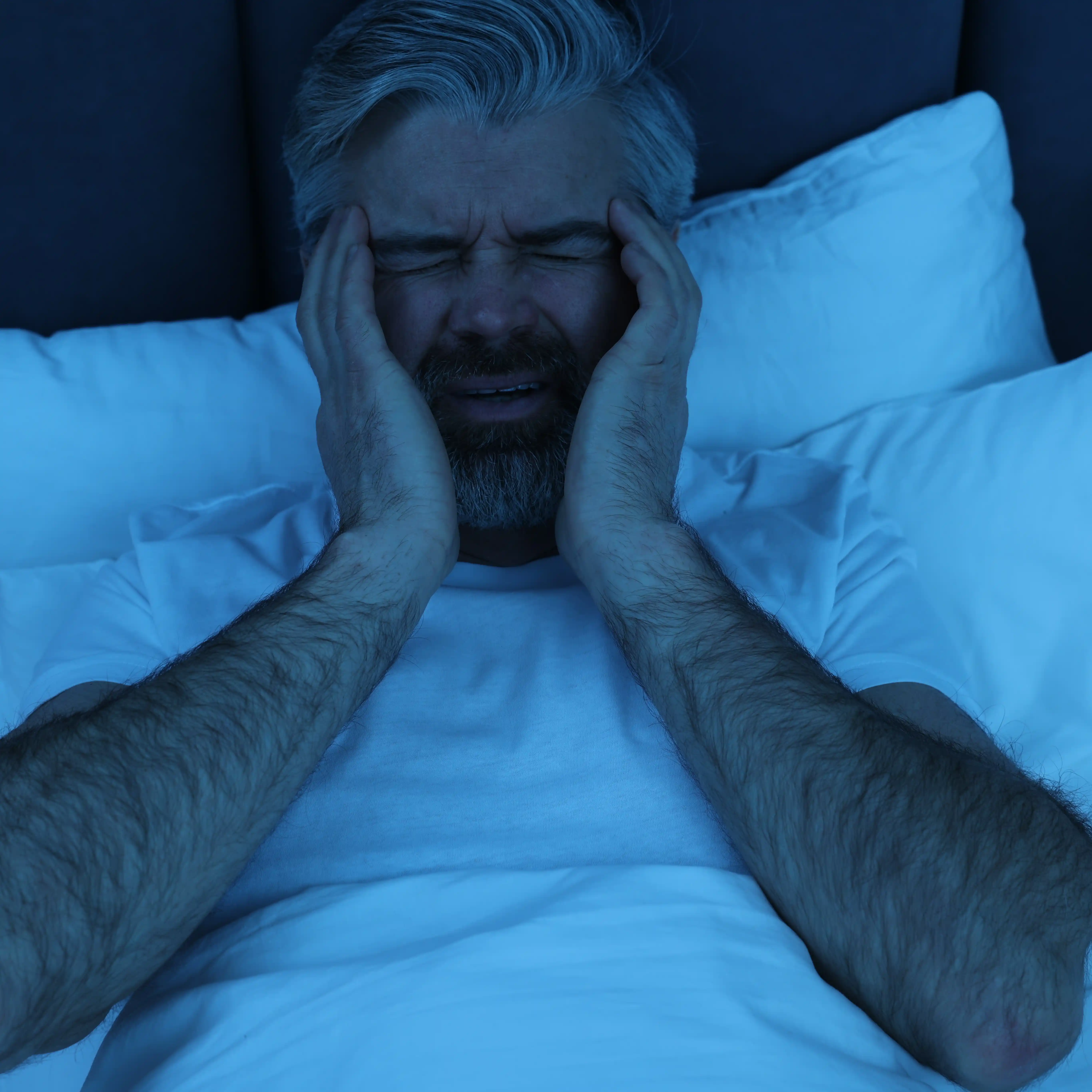A middle-aged man is awake in bed in the middle of the night. He’s going through nicotine withdrawal and can’t sleep.
