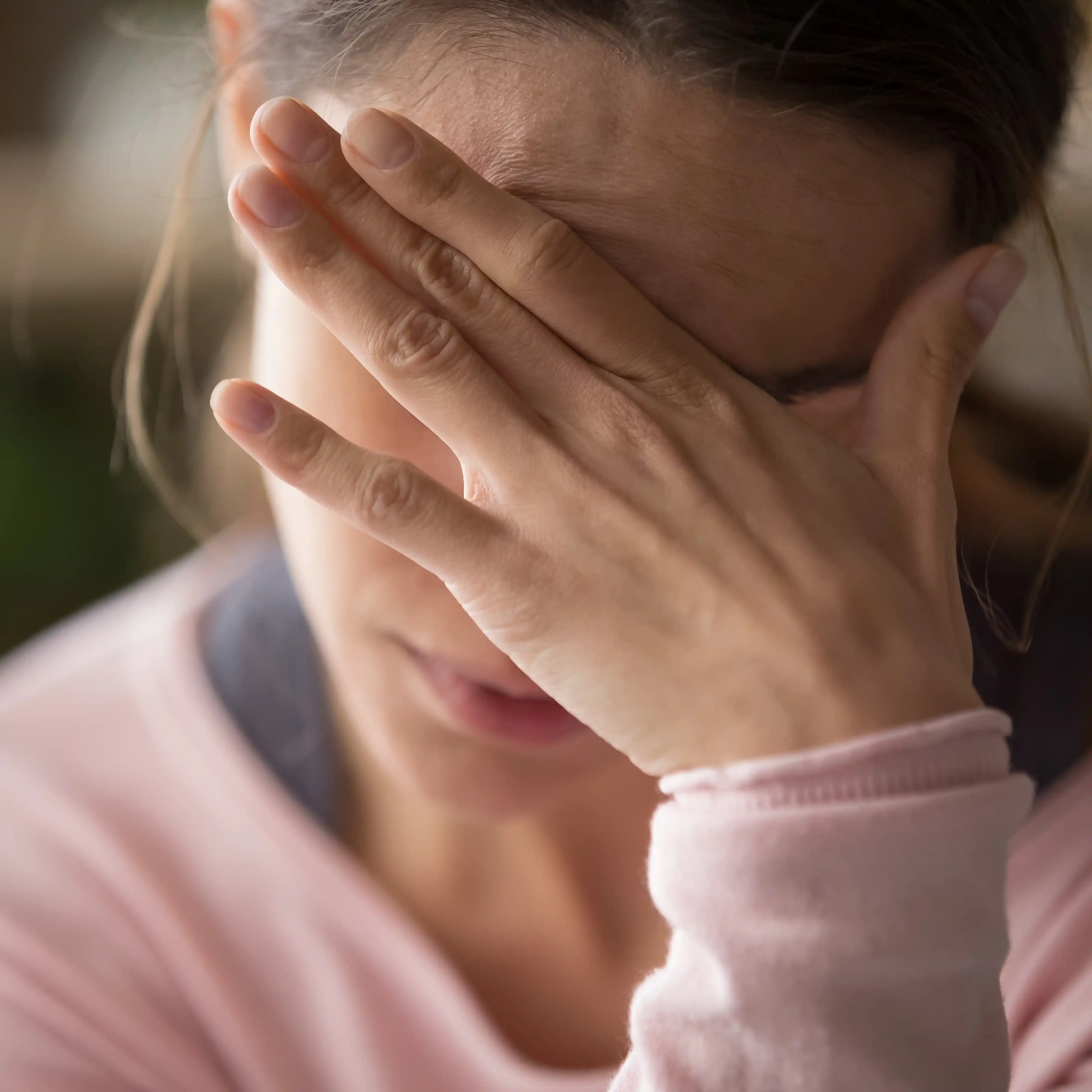 A woman sits in a therapy session at The Hader Clinic, rubbing her forehead in frustration as she works through anger and emotional triggers. 
