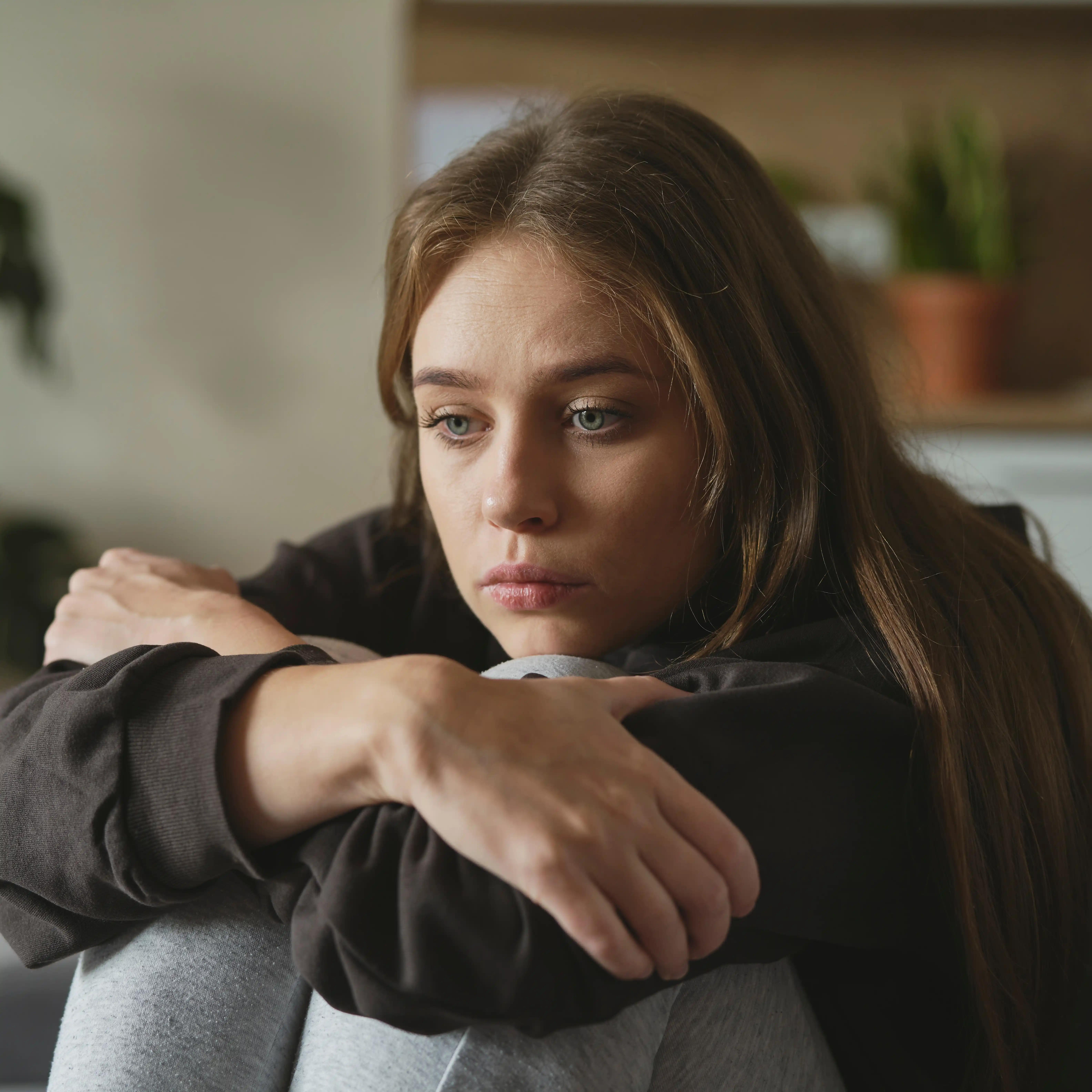 A woman sits quietly on a sofa during her inpatient stay at The Hader Clinic, reflecting on the emotional lows of bipolar disorder and beginning her recovery.