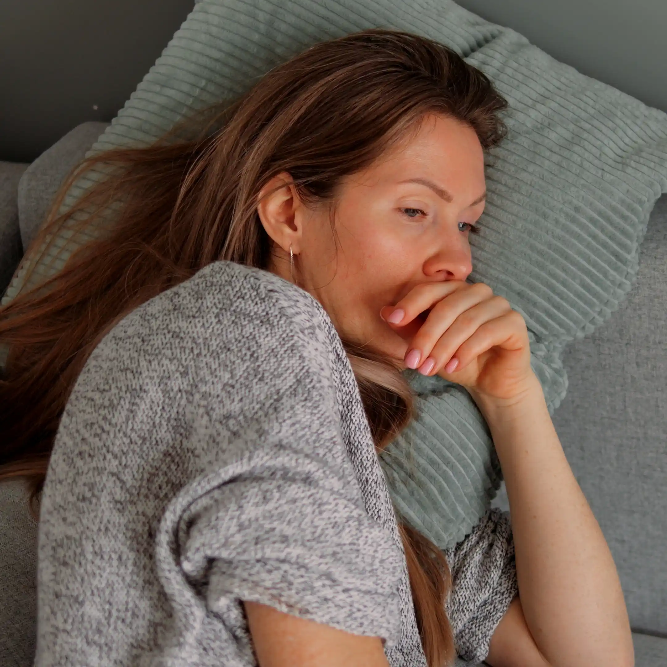 A middle-aged woman lies on a couch deep in thought during inpatient care at The Hader Clinic, working through the emotional confusion of her disorder and substance use.