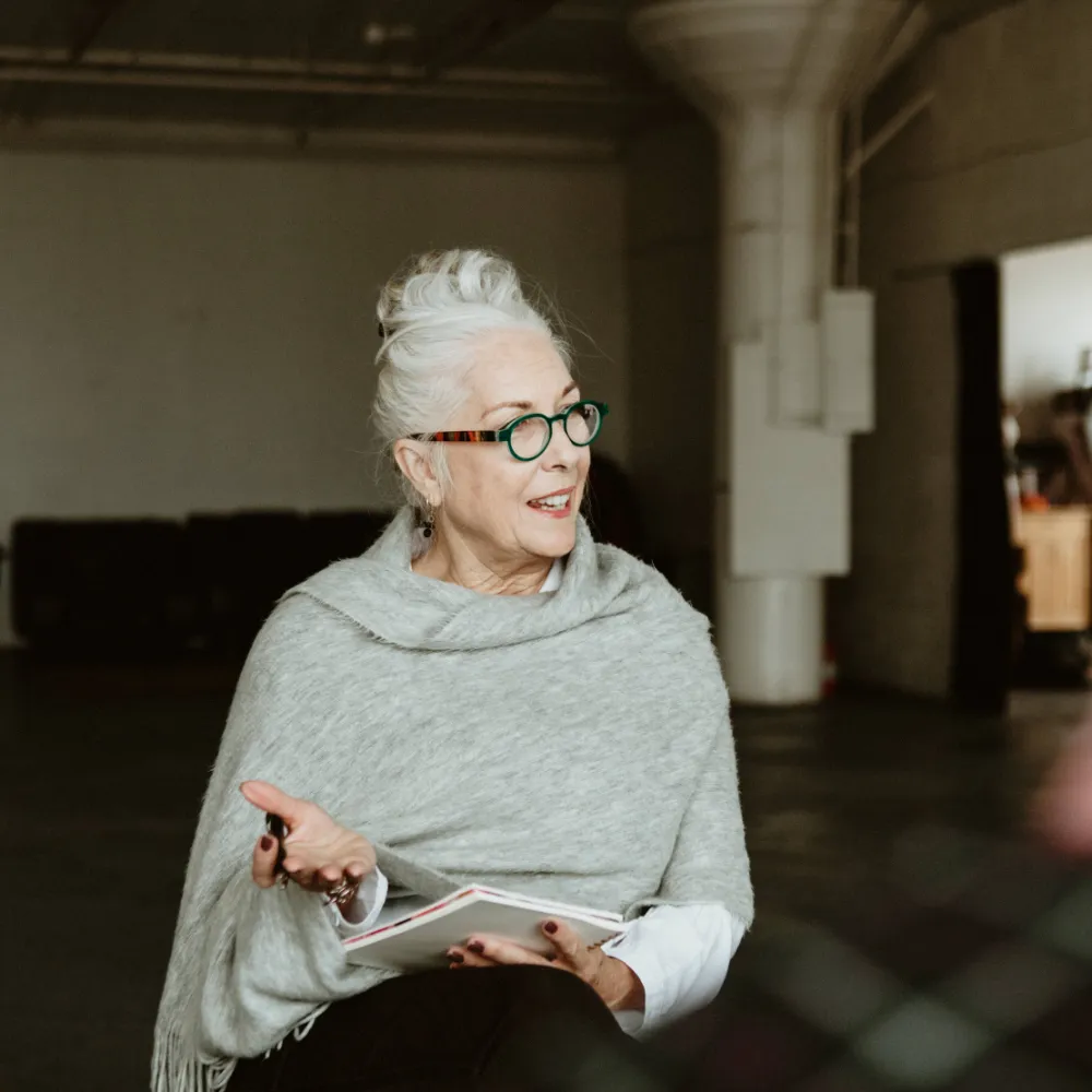 A group therapy session for inpatient residents. An older female therapist is speaking to the group about the challenges and rewards of addiction recovery.