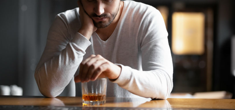 young man nurses a glass of whisky