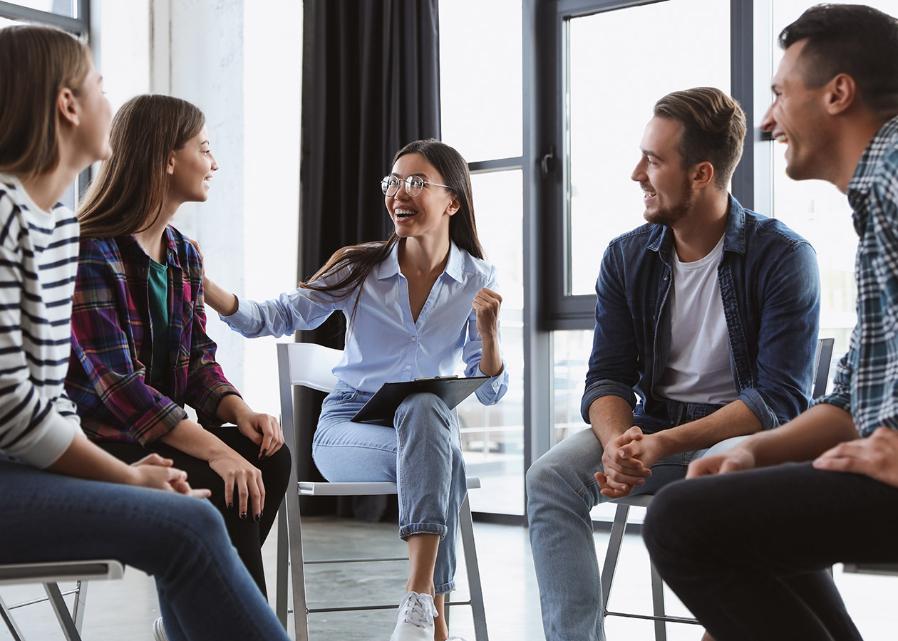 A diverse group of people huddled in a circle during rehab for adults.