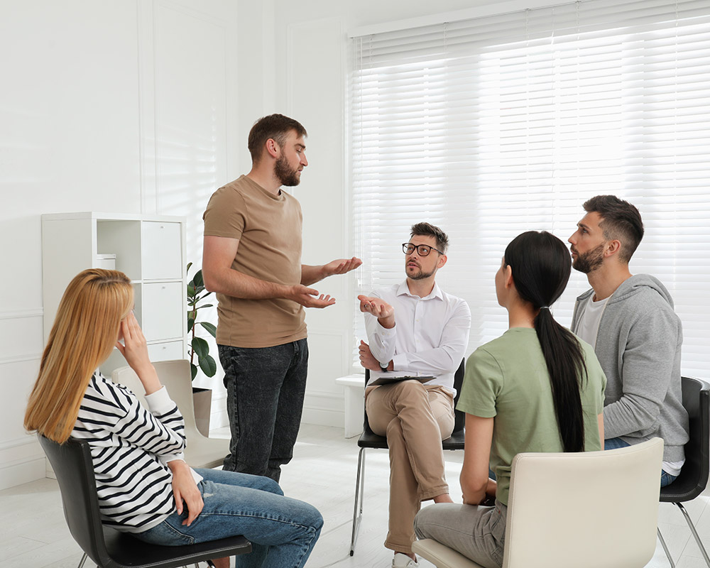 A psychotherapist working with a group of people undergoing recovery treatment