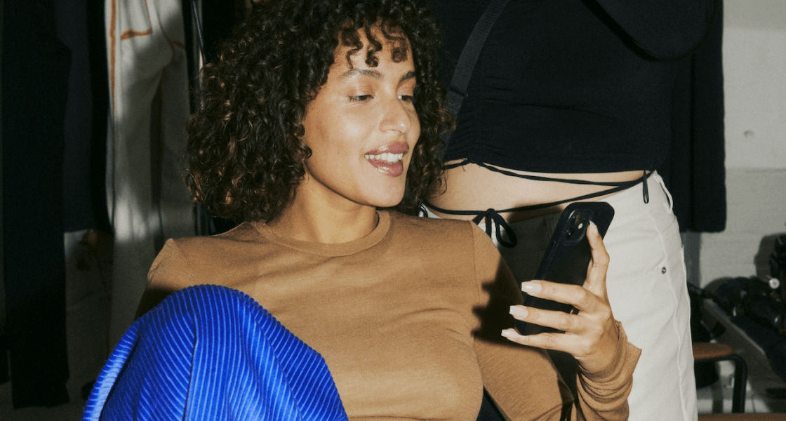 Smiling woman watching a Bambuser live video on her phone.