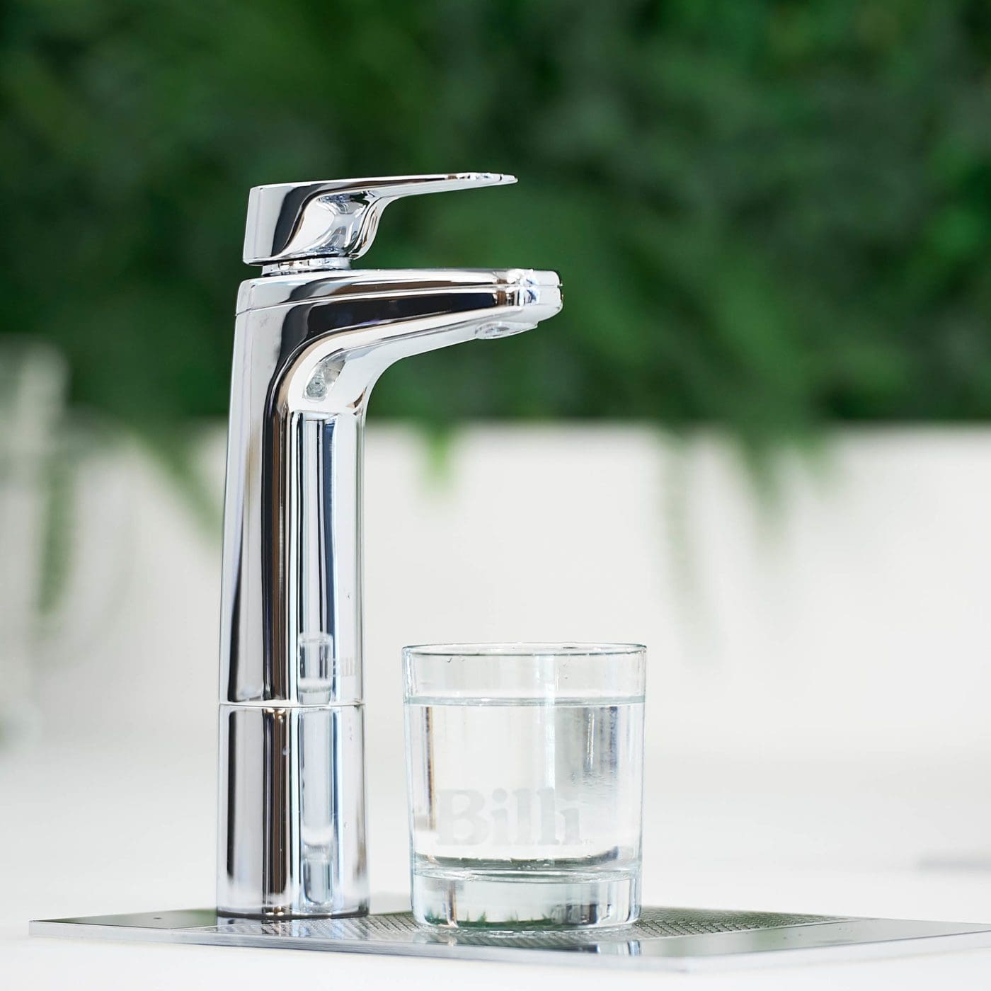 Chrome Billi XL levered dispenser with a glass of filtered water on a drip tray