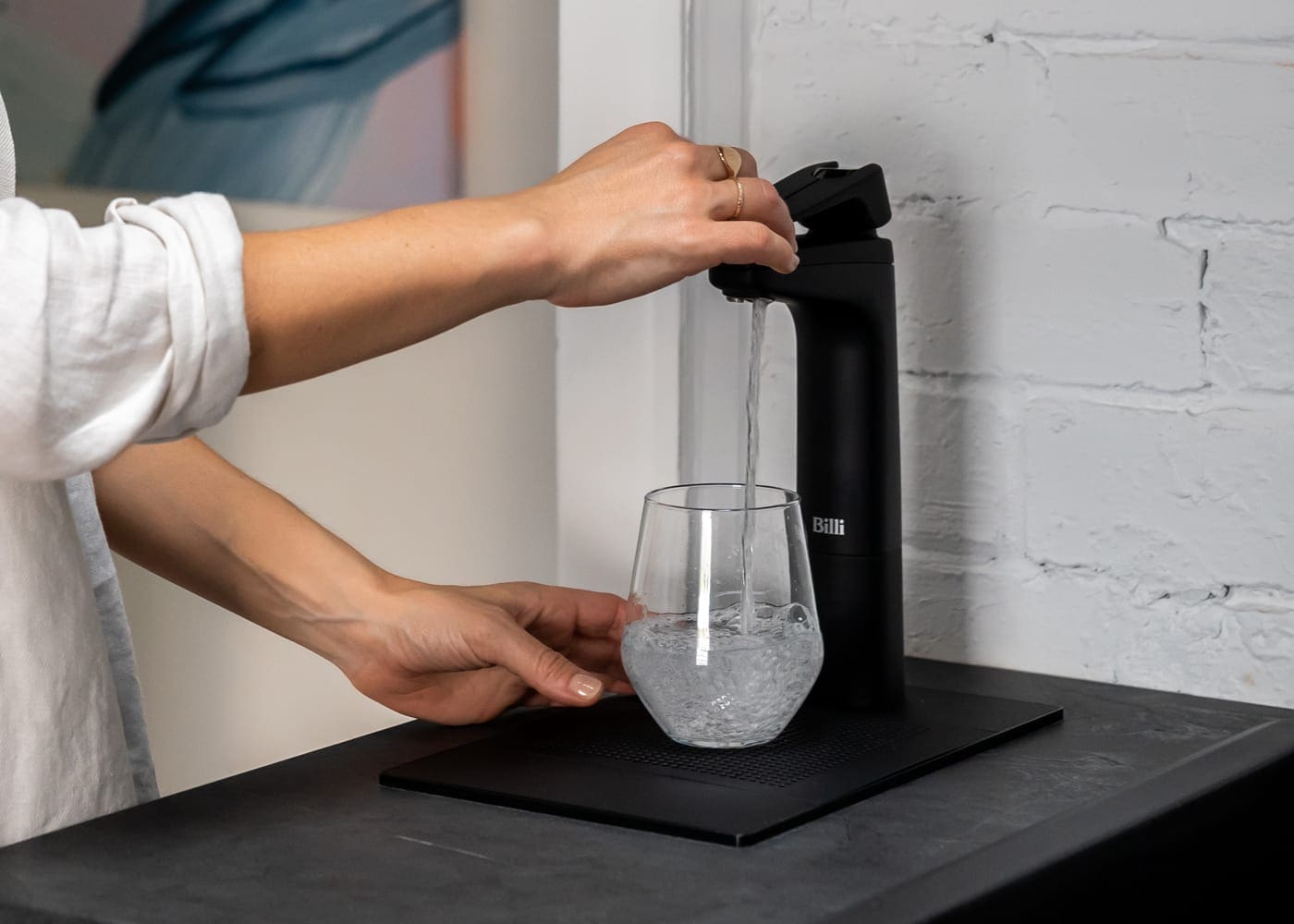 Billi XL levered dispenser in matte black filling a glass with filtered water