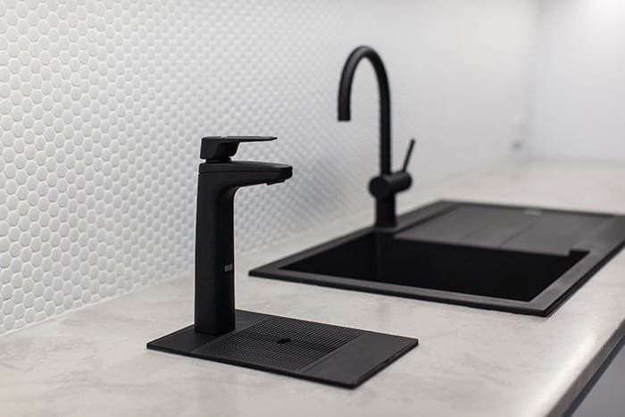 Matte black Billi XL levered dispenser beside a black kitchen sink