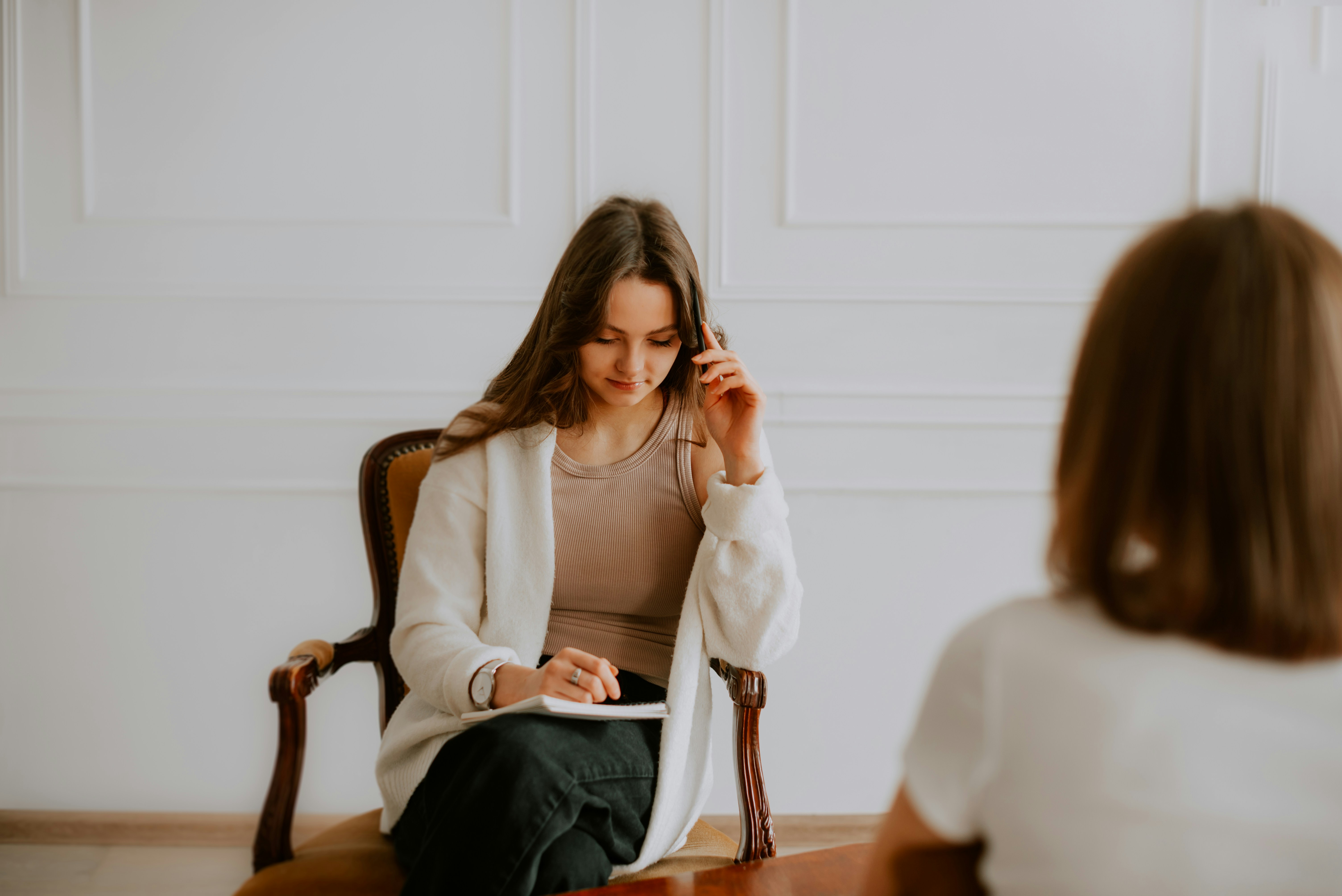 Therapist thoughtfully listening and writing notes, an example of authentic interaction photos that help clients feel connected before booking a session.