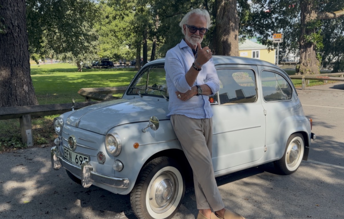 Mats Lindberg med solglasögon och ljusblå skjorta vid sin ljusblå Fiat 600.