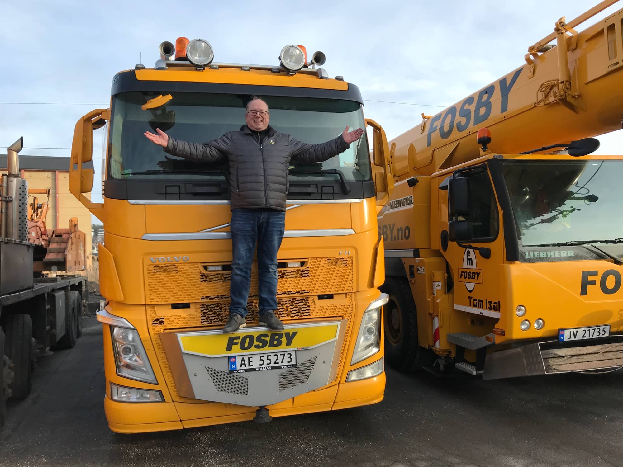 Fosby-medarbeider står på fronten av lastebil foran mobilkran