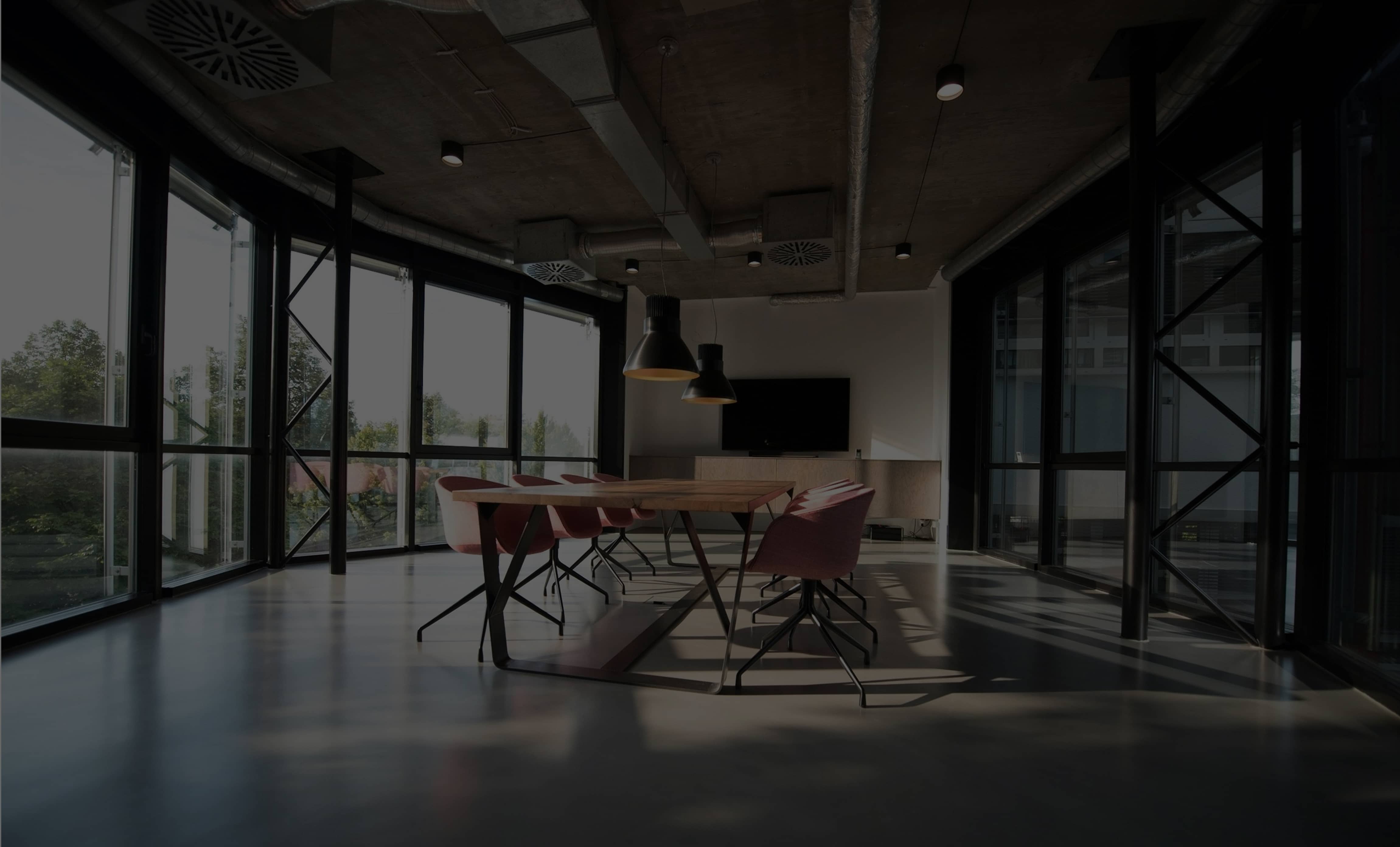 Modern, bright conference room with an empty table and natural light streaming through expansive windows