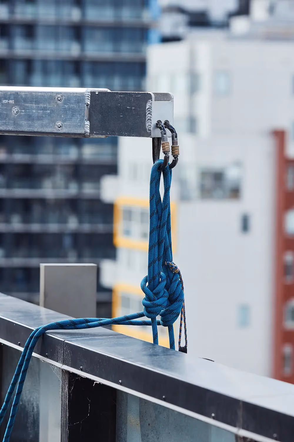 A close-up of a suspension rope secured to the anchor point on the end of a davit arm on the roof of a highrise building.