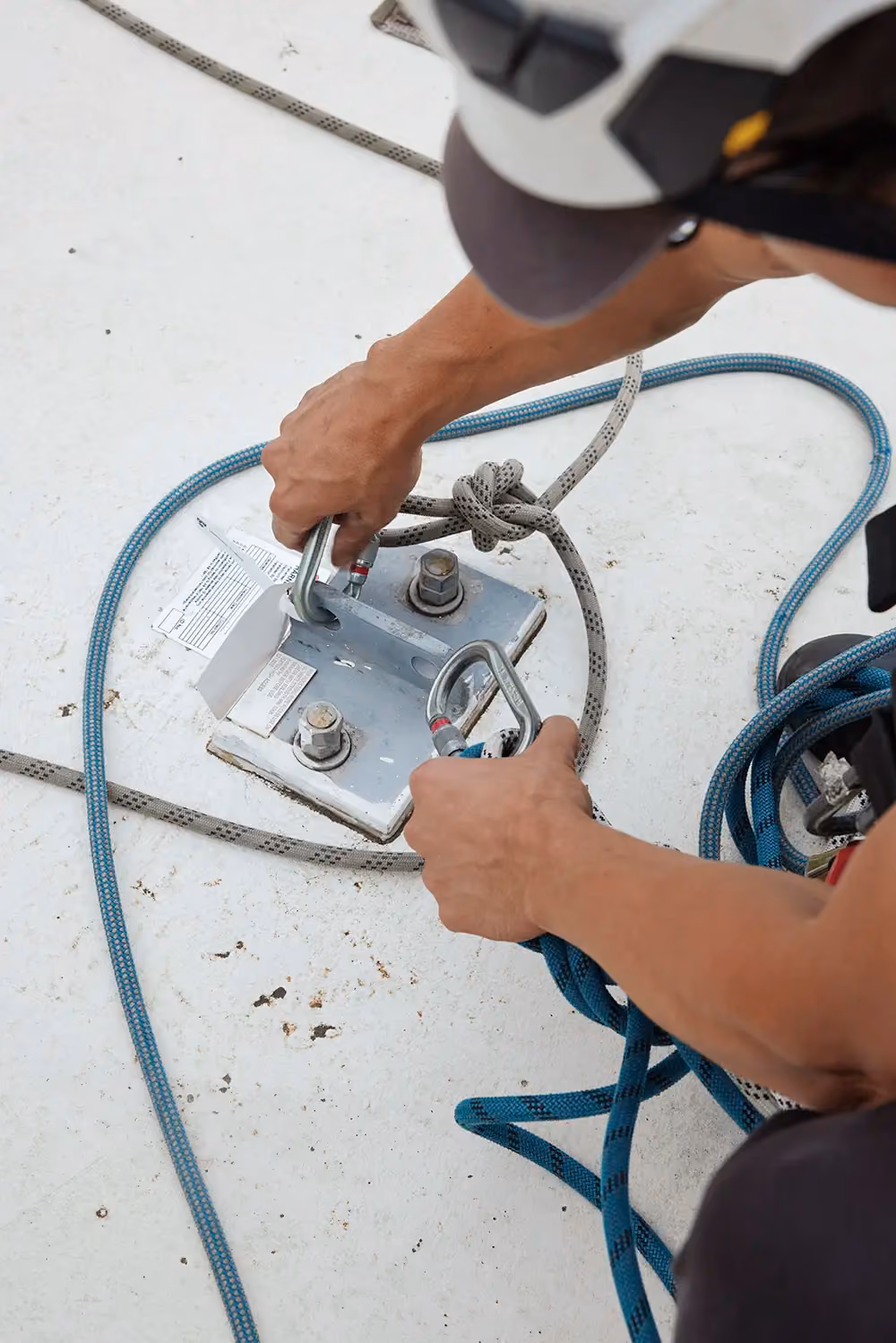 A close-up of a Bax specialist’s hands as tests a roof anchor point that he’s just installed.