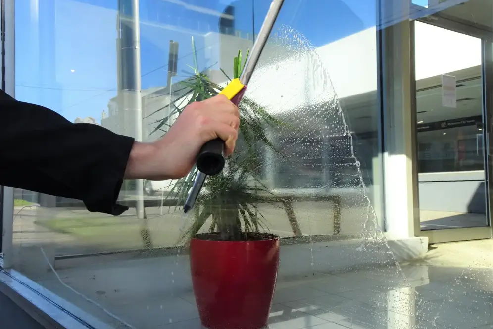 Close-up of a person using a squeegee to clean a glass window.