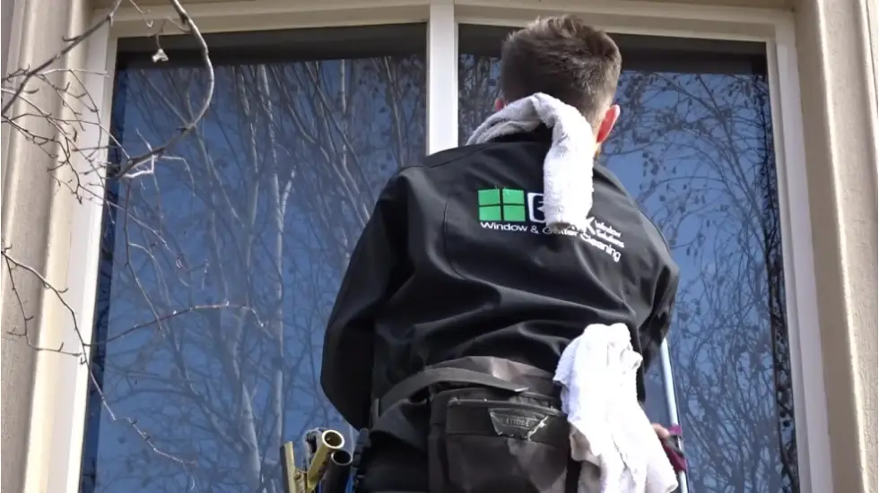 Worker wearing a Bax Clean jacket cleaning an exterior window.