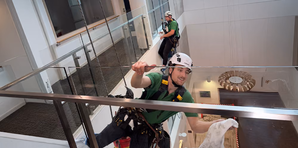 Rope access technicians cleaning high-level glass and interior windows at an aged care facility.