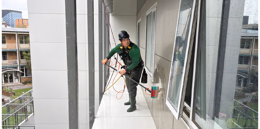 Bax Clean technician cleaning exterior windows and façades at an aged care facility using rope access techniques.