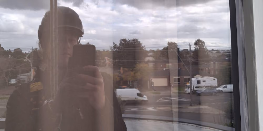 Reflection of a rope access technician inspecting exterior windows during the cleaning process.