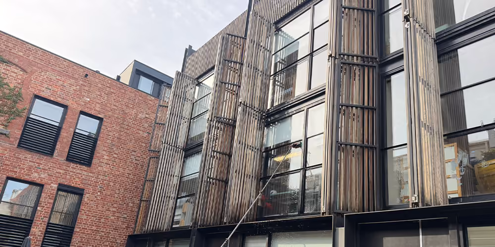 Exterior window cleaning underway using an extension pole at the West Melbourne residential complex.