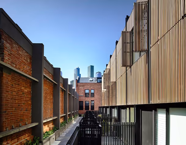 Walkway between heritage brick buildings and modern residences in the West Melbourne residential complex.