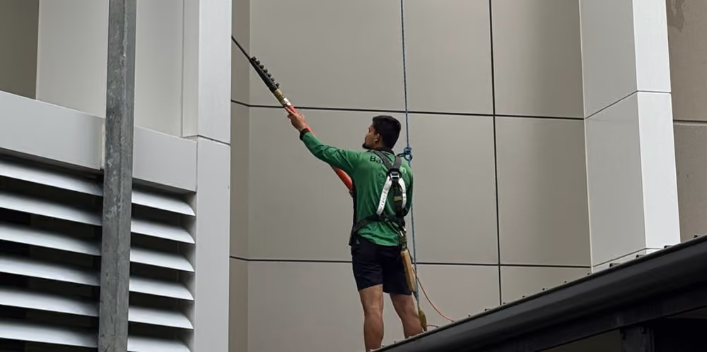 Technician cleaning exterior cladding panels using an extension pole at the premium retirement complex.