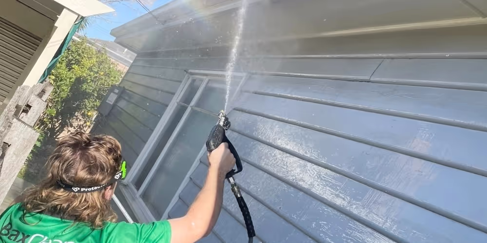 Bax Clean technician pressure washing rendered exterior walls to remove grime and organic buildup in Oakleigh.