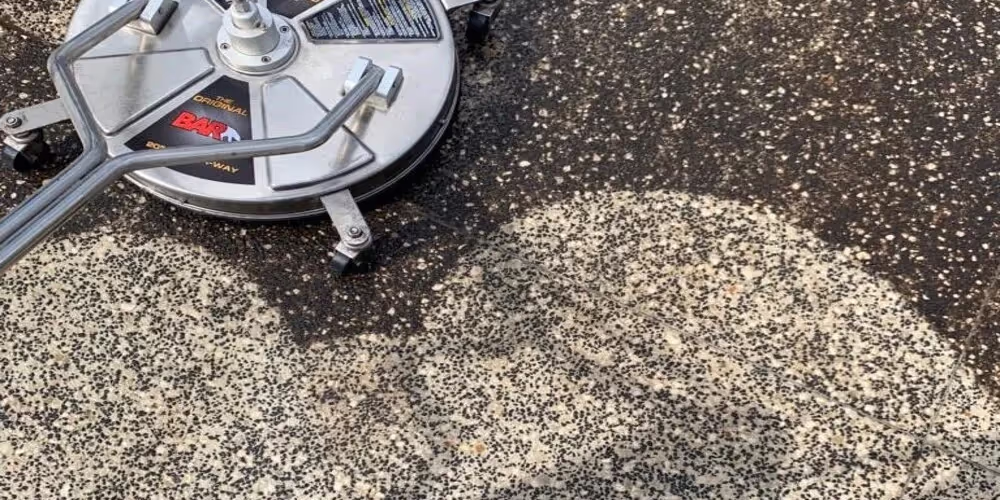 A technician pressure washing a concrete driveway to remove built-up grime, moss, and stains in Box Hill.