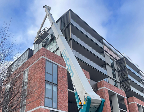 Elevated boom lift reaching the upper façade of Ardency Kennedy Place during high-access window cleaning.