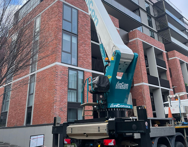 Boom lift positioned beside Ardency Kennedy Place to access upper-level windows for external cleaning.