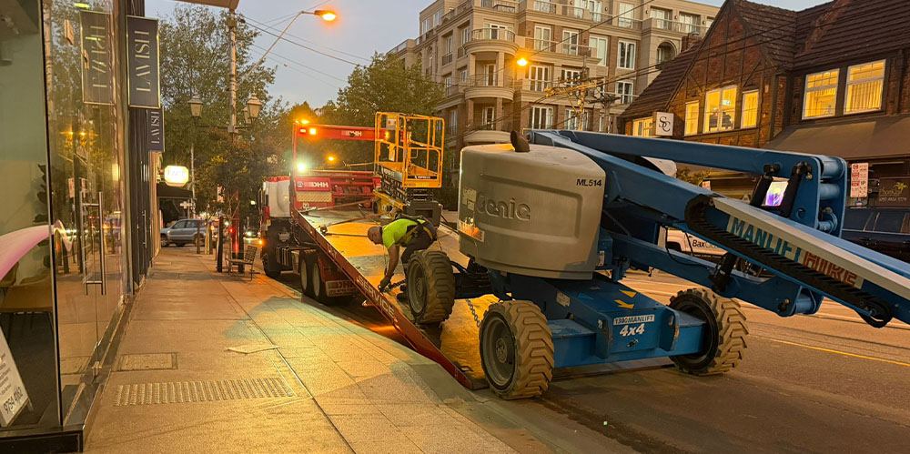 Elevated work platform being loaded onto a transport truck after completing an exterior restoration project.