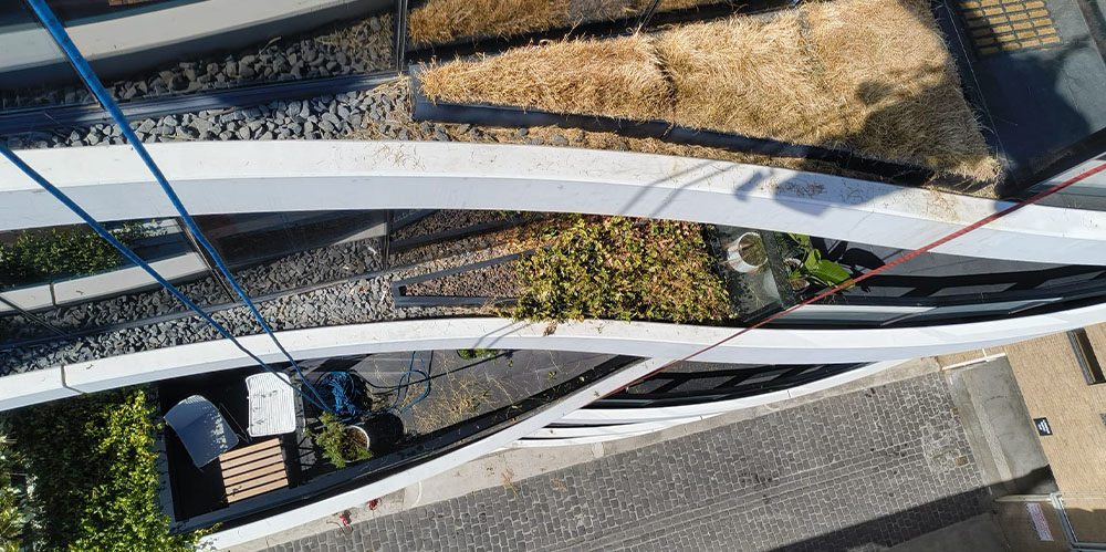 Curved apartment balconies with elevated planter boxes viewed from above during exterior maintenance works.