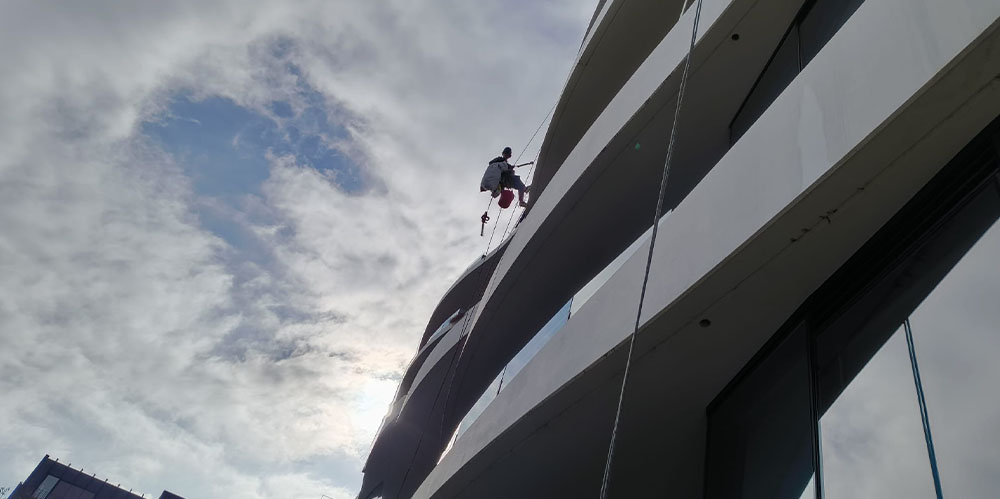 Rope access technician cleaning the exterior of a curved high-rise apartment building in South Melbourne.