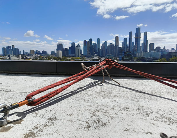 Rope access anchor system secured on a rooftop overlooking the Melbourne CBD skyline.