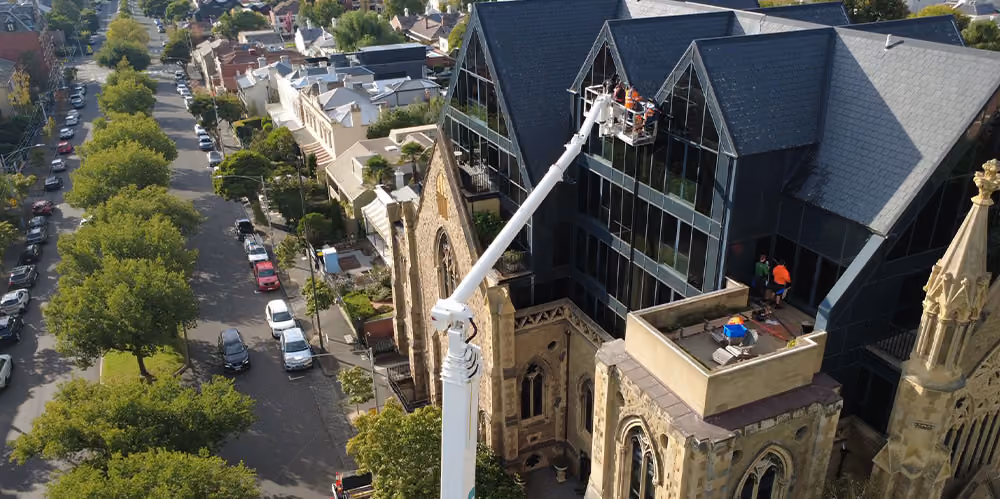 Drone view of high-access exterior cleaning, combining heritage architecture with modern glass extensions.