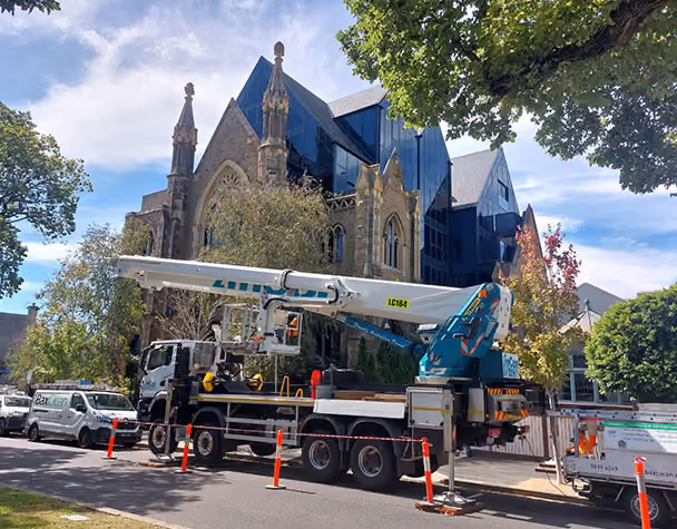 Technician cleaning exterior glass at the Iconic East Melbourne Apartments using rope access methods.