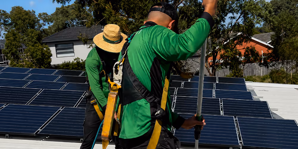 Technicians using specialised equipment to clean rooftop solar panels safely and efficiently.