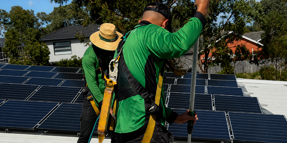 Technicians using specialised equipment to clean rooftop solar panels safely and efficiently.