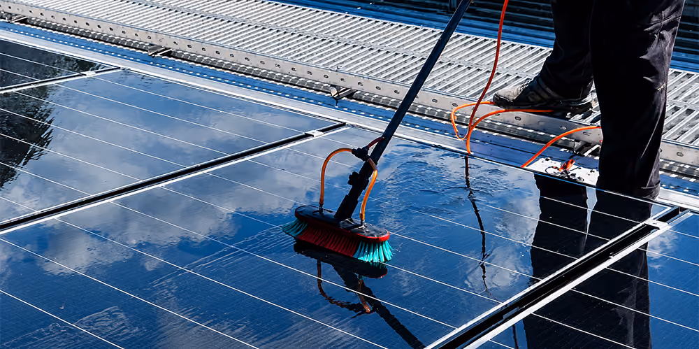 Technician cleaning rooftop solar panels with a water-fed brush system at a commercial property in Nunawading.