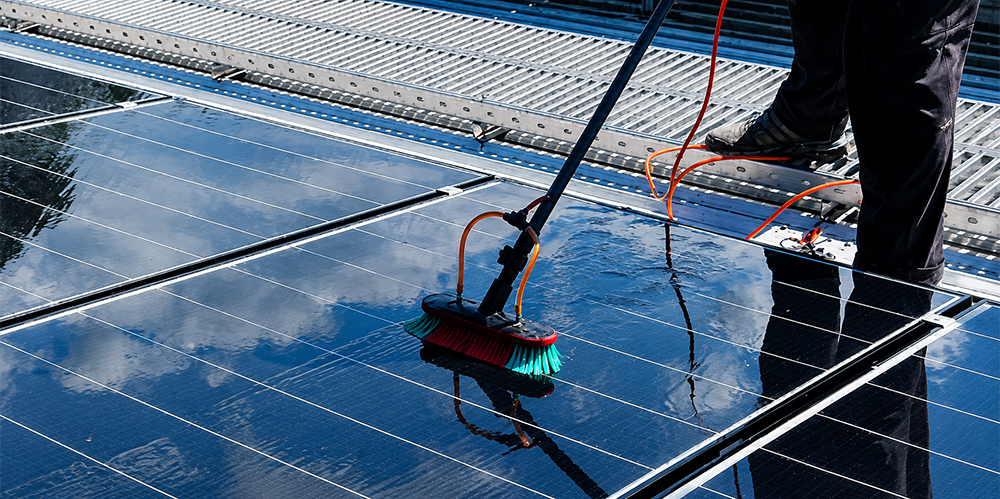 Technician cleaning rooftop solar panels with a water-fed brush system at a commercial property in Nunawading.
