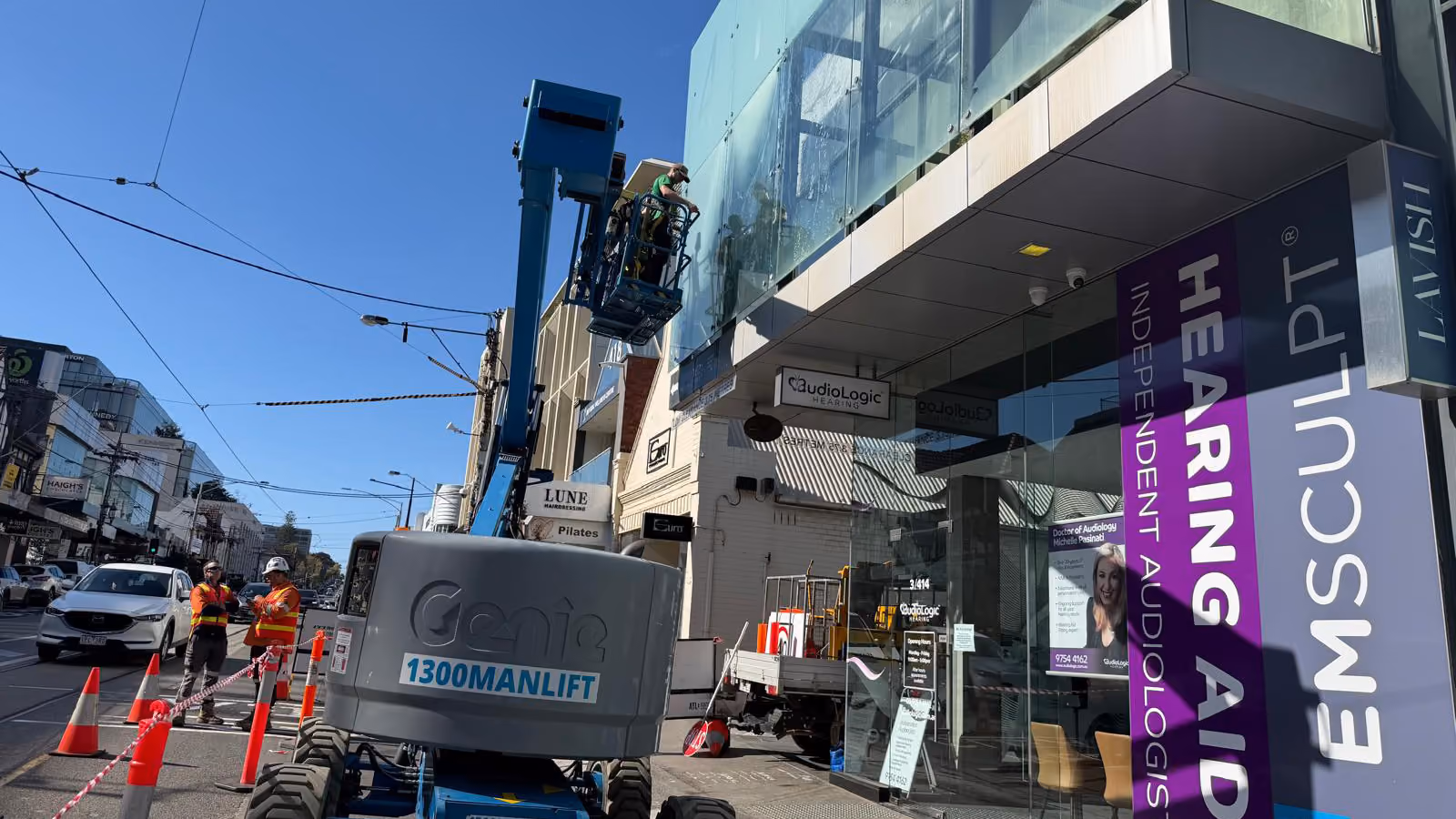 Technician cleaning exterior glass windows beneath a covered walkway at a commercial office building in Toorak.