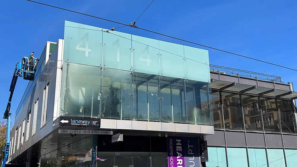 Bax Clean technician using an elevated work platform to clean commercial building windows