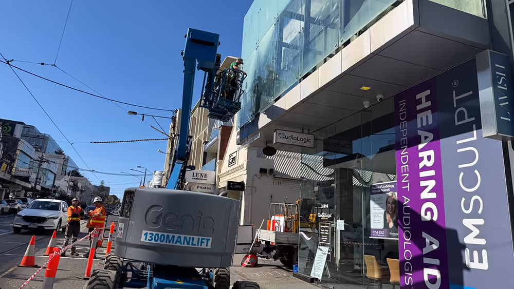 Bax Clean technician cleaning high-level windows from an elevated work platform